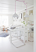 Transparent cantilever chairs around folding table in white dining room