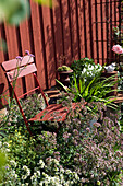 Red folding bistro chair in the middle of a perennial bed