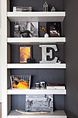 Decorative letters and photos of children on floating shelves on dark wall