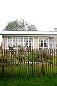 Picket fence in front of a house with a summer garden