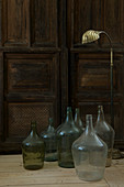 Wine jugs and a golden floor lamp in front of an old wooden door