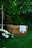 Badewanne aus Holz auf der Wiese im sommerlichen Garten