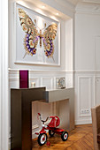 Picture of butterfly above modern console table and tricycle