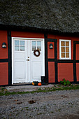 Rotes Fachwerkhaus mit Reetdach am Kiesweg im Herbst