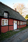 Rotes Fachwerkhaus mit Reetdach am Kiesweg im Herbst