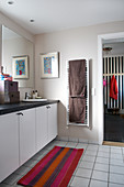 Colourful striped runner in plain bathroom with sink in long base cabinet