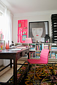Pink chair on the old wooden table in front of the half-height shelf in the study