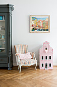 Baroque chair, painting of Mediterranean town and dolls' house on herringbone parquet floor