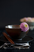 Brown ceramic bowl with wooden sticks and purple chrysanthemum