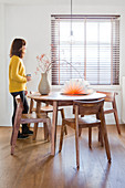 Woman at the window in the simple dining room with wooden furniture