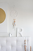 White bed headboard below decorative letters and dreamcatcher on wall