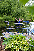 Bistro table and chairs on a wooden deck by the pond