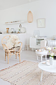 Rattan chair with sheepskin rug, tables and sideboard in white living room