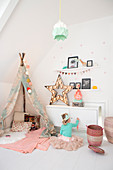 Little girl wearing tutu sitting next to play wigwam in vintage-style bedroom