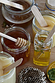Different types of honey in glasses with wooden craft sticks and honey dipper