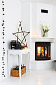 Corner of a room with side table and fireplace decorated for Christmas