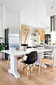Open kitchen in white with dining table, kitchen island, and shelf with wooden sliding barn doors