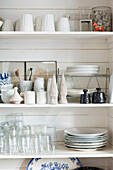 White kitchen shelf with stoneware, glasses, and kitchen utensils