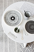 Round table with black and white stoneware on carpet with graphic pattern