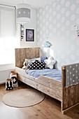 Reclaimed wood twin bed in front of dotted wallpaper