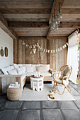 A boho lounge in a rustic loggia with wooden walls