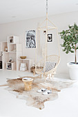 Hanging chair and side table on cowhide, shelf modules in the background