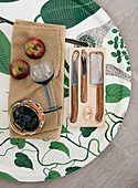 Knife, apples, thistle, and wine glass on a tray with a floral pattern