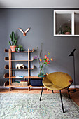 Vintage suede armchair and cabinet shelf against a gray wall