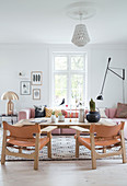 Pink upholstered sectional sofa, golden table lamp, rustic coffee table, and leather chairs in the living room