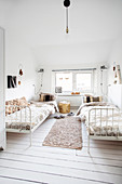 Bedroom in white with two metal beds and wooden floor