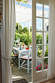 A view through open French windows of a table laid on the terrace