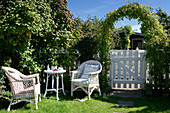 seating area in the garden with wicker furniture next to the garden gate under the climbing arch