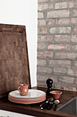 Crockery on a wooden worktop in front of a brick wall