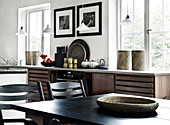Black lacquered wooden table with chairs, in the background the kitchenette in front of the window