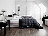 Queen bed with black quilt and white built-in wardrobe in the bedroom
