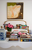 View past books on coffee table to antique sofa with white cover below painting