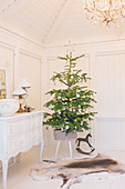 Weihnachtsbaum auf einem Hocker neben weißer Kommode