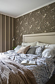 Double bed with headboard in bedroom with brown wallpaper