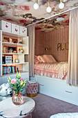 Girl's bedroom decorated in pink with cubby bed and bookcase