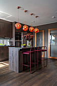 Elegant kitchen with dark wooden fronts and velvet bar stools at kitchen island
