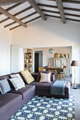 Sofa im mediterranen offenen Wohnraum mit Balkendecke