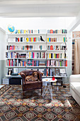 Alter Ledersessel mit Hund vor Bücherwand im Wohnzimmer mit buntem Fliesenboden