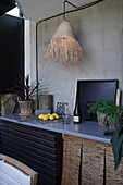 Raffia lampshade above worksurface of outdoor kitchen