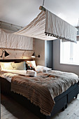 Schlafzimmer in Naturtönen mit Baldachin und Holzverkleidung