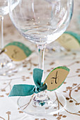 Handmade, leaf-shaped paper tags with initials tied to glasses