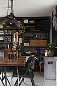Dining table and black folding chairs in front of rusty metal shelves