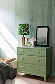 Green chest of drawers against wall with woodland motif in bedroom