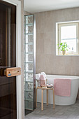 Modern, free-standing bathtub behind glass-brick partition