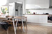 Fur blankets on designer chairs at dining table in modern kitchen-dining room