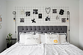 Double bed with grey headboard below metal mesh used to hang ornaments and lamps
